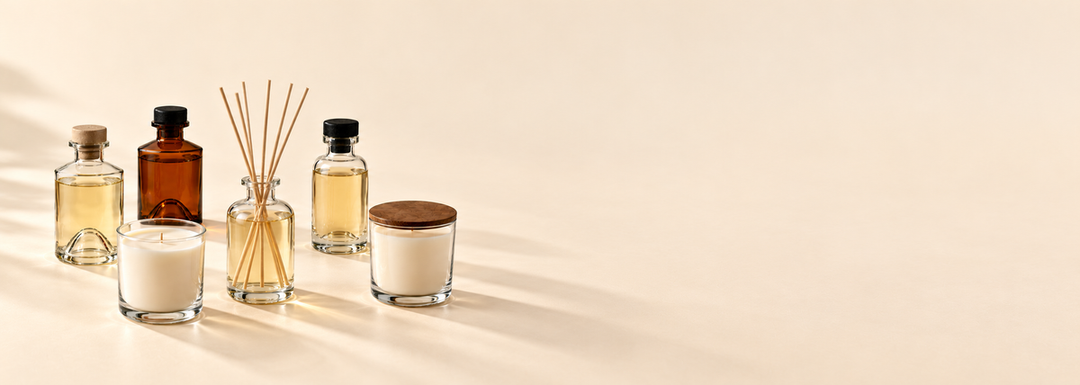 Italian glass diffuser bottles and candle jars on an ivory tabletop